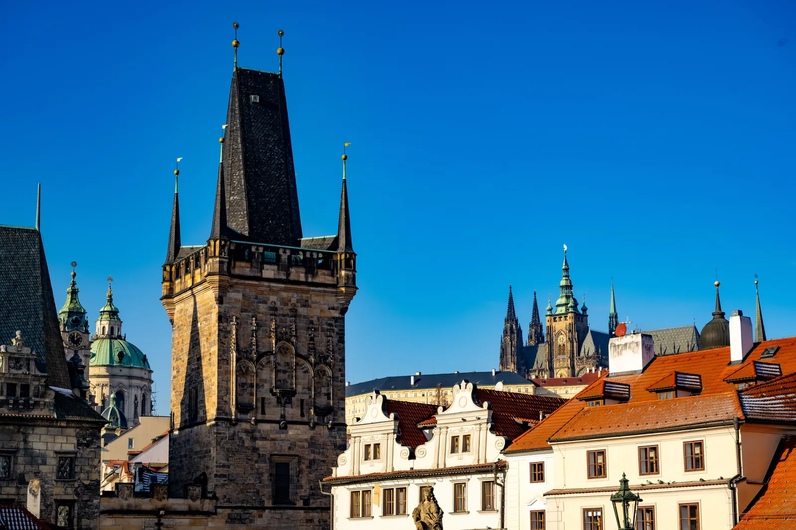 Les toits de la vieille ville de Prague au coucher du soleil, le château au loin
